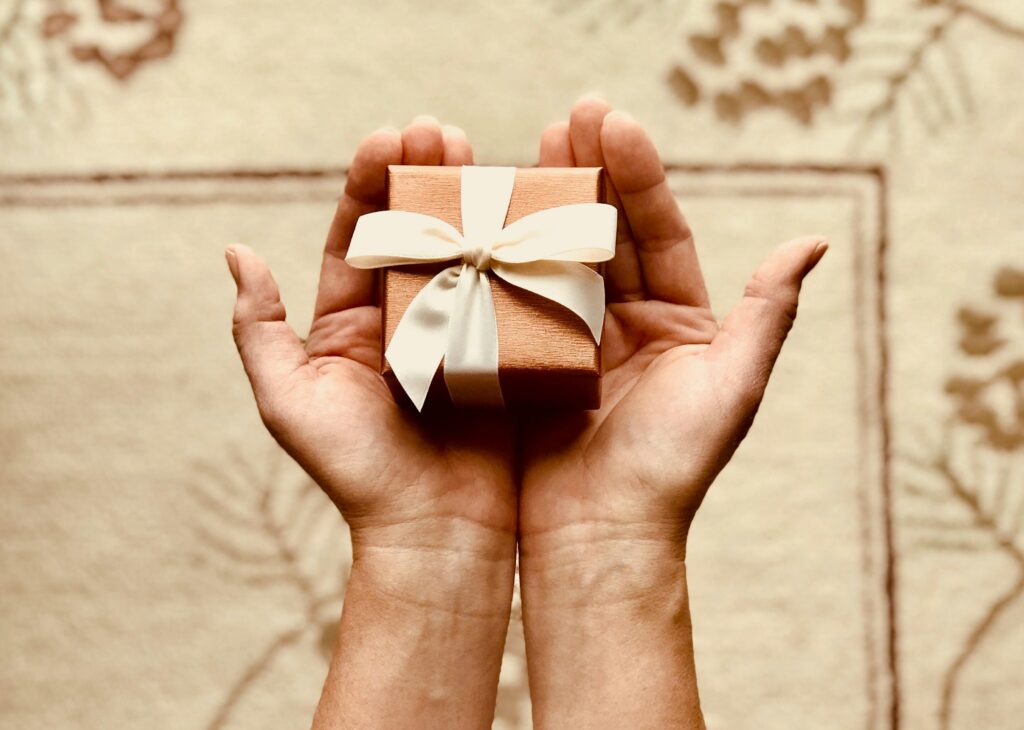 A small gift box with a bow in hands.